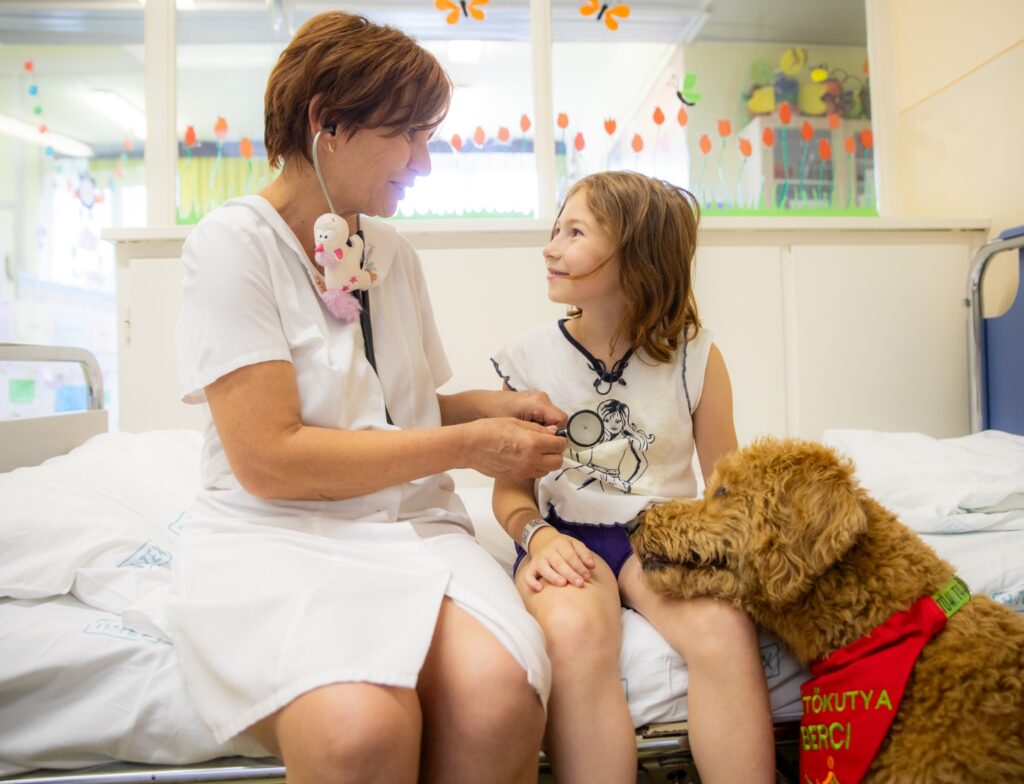 Dr. H. Nagy Katalin Csecsemő- és gyermek szakorvos Berci nevű segítőkutyájával vizsgálja egyik kis betegét, Mák Izabellát az Orosházi Dr. László Elek Kórház Csecsemő- és Gyermekosztályán. Fotó: Nagy Kristóf 2025 07 07